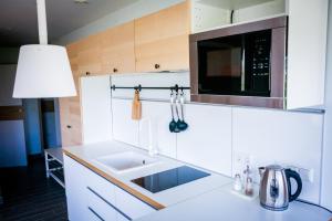 a white kitchen with a sink and a microwave at Vila Nikolas in Druskininkai