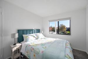 Habitación blanca con cama y ventana en Teemos Retreat - Family and Friends, lots of space, big backyard en Rotorua