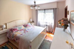 1 dormitorio con 1 cama y un jarrón de flores en Casa Juliana, en Ribadavia