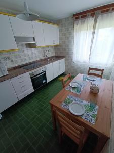 a kitchen with a wooden table with chairs and a kitchen with white cabinets at La Cruz del Sur in Sanxenxo