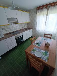 a kitchen with a wooden table with chairs and a kitchen with white cabinets at La Cruz del Sur - "ONS" in Sanxenxo +19 photos