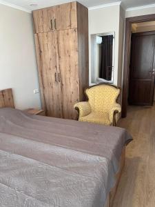 a bedroom with a bed and a chair and a cabinet at Villa Premium Shekvetili in Shekhvetili