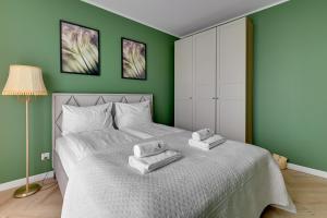 a green bedroom with a bed with towels on it at Willa Dattero Gdynia by Lion Apartments in Gdynia