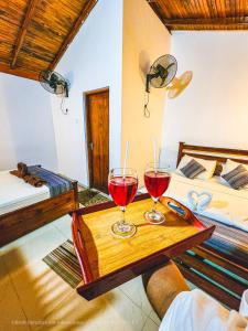 two glasses of red wine on a wooden table in a room at Birds Paradise Inn in Udawalawe