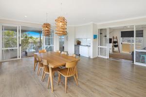 cocina y comedor con mesa de madera y sillas en Spinnaker Quays en Mooloolaba