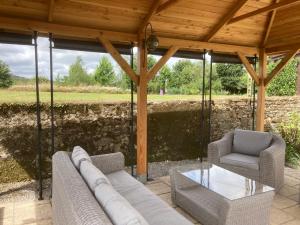 eine überdachte Terrasse mit 2 Stühlen und einem Glastisch in der Unterkunft La Vieille Laiterie in Plessala