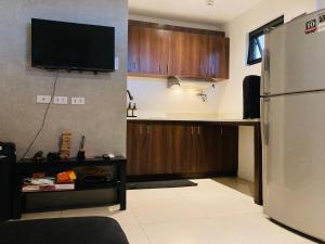 a kitchen with a refrigerator and a tv on the wall at Barkada Room 1 near Clark (Casa Isabela) in Mabalacat