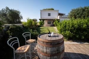 a wine barrel with chairs and a house in the background at TERRA TERRA - Masseria Minunni in Conversano