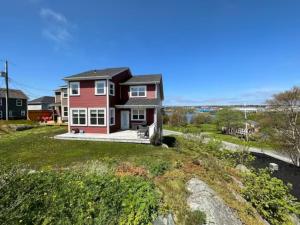 a red house on a hill with a yard at Experience Coastal Charm-The Vista At Quidi Vidi! in St. John's
