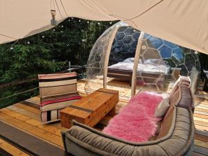 une terrasse avec une tente, un canapé et une table dans l'établissement Glamping Štôla- Perzeid, à Štôla