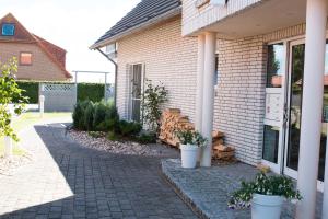 a house with a brick walkway and potted plants at Apartment "Suites" Biermann in Garding