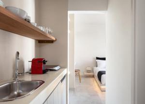 uma cozinha com um lavatório e um quarto com uma cama em Kythea Suites Kythnos em Kythnos