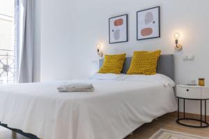 ein Schlafzimmer mit einem großen weißen Bett mit gelben Kissen in der Unterkunft Luxurious 2BR/2BA in Chueca in Madrid