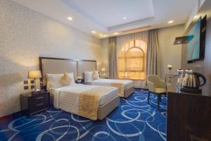 a hotel room with two beds and a desk at Cloud City Hotel in Al Baha +39 photos