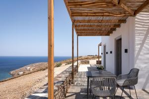 een patio met een tafel en stoelen en uitzicht op de oceaan bij Kythea Suites Kythnos in Kithnos