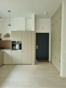 uma cozinha com armários brancos e uma porta preta em Baltivia Haus em Gdynia