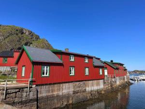 un edificio rosso accanto a un corpo idrico di Stamsund Harbour Apartment a Stamsund