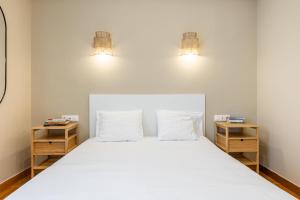 um quarto com uma grande cama branca com duas mesas de cabeceira em Kolonaki Suites by Olala Homes em Atenas