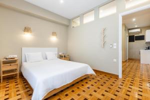 a bedroom with a white bed and a wooden floor at Kolonaki Suites by Olala Homes in Athens