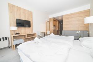 - une chambre avec un grand lit blanc et un bureau dans l'établissement VacationClub - Aparthotel Czarna Góra 309, à Sienna