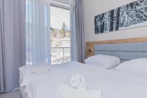 1 dormitorio con 1 cama con sábanas blancas y ventana en VacationClub - Aparthotel Czarna Góra 221, en Sienna