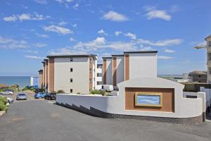 a building with a sign in a parking lot at West Beach - Holiday Apartments in Westward Ho