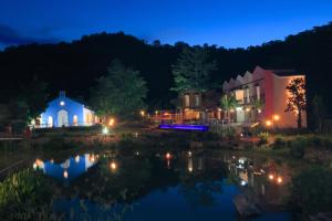 a town at night with a reflection in the water at Ville De La Vie Khao Yai in Mu Si