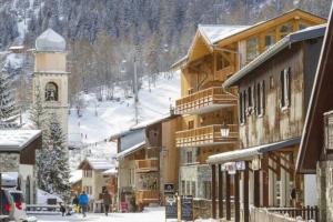 a snow covered town with a ski lodge and a ski slope at Powder Ridge - 6 bedroom chalet with hot tub in Tignes