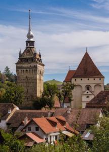 uma cidade com uma torre de relógio e um edifício em Castle View em Saschiz