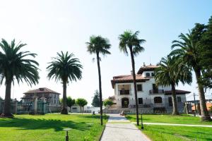 a group of palm trees in front of a house at Hotel El Rosal de Cudillero in Cudillero