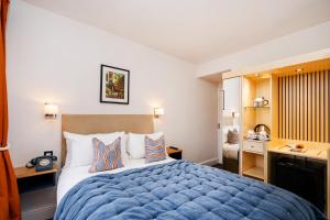 1 dormitorio con cama azul y escritorio en The Rodney Hotel, en Bristol
