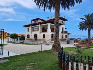a house with a palm tree and a fence at Hotel El Rosal de Cudillero in Cudillero