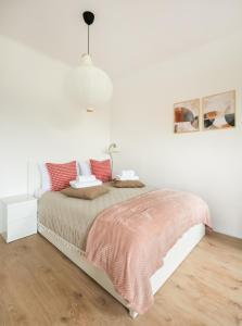 a white bedroom with a bed with red pillows at Polna Centrum Studio in Warsaw