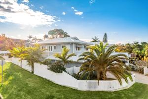 uma casa branca com palmeiras em frente em Villa Wallah Luxury in Byron Bay em Byron Bay