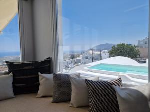 a room with a large window with a view of a pool at Amerisa Suites & Villa in Fira