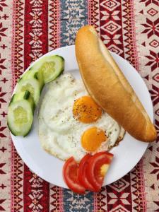 a plate with eggs and a hot dog and a pickle at Catba Papillon Garden Bungalows & Resort in Cat Ba