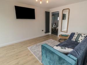 a living room with a blue couch and a mirror at 1 Staveley Cottages in Weaverthorpe