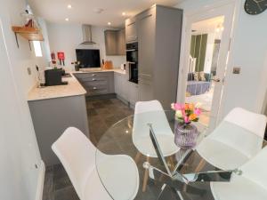a kitchen with white chairs and a glass table at 1 Staveley Cottages in Weaverthorpe