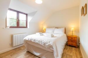 a bedroom with a large white bed and a window at Tystie Cottage in Salthouse