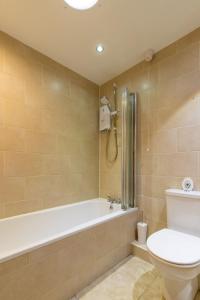 a bathroom with a toilet and a bath tub at Tystie Cottage in Salthouse