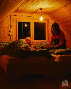 a man and a woman sitting on beds in a room at Waldhütte Kosak in Trofaiach