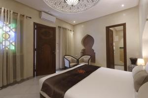 a bedroom with a large white bed with two chairs at Riad Mandana & Spa in Marrakesh