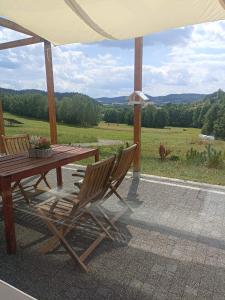 a wooden table and chairs sitting under an umbrella at Maraśka Holiday House in Kamienna Góra