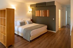 a bedroom with a large bed and wooden floors at Vila Bicuda Resort in Cascais