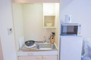 uma pequena cozinha com um lavatório e um frigorífico em 閑静な住宅街_暖かく居心地の良いデザイン YoW-4 em Tóquio
