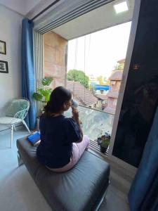 Kobieta siedząca na kanapie grająca w grę wideo w obiekcie Angel Views 201, Chapel Road, Bandra West by Connekt Homes w Bombaju