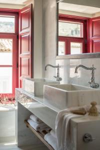 a white bathroom with two sinks and red windows at FOS Hydra residence in Hydra