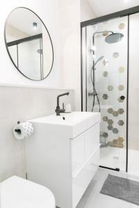 a white bathroom with a sink and a shower at VacationClub – Ogrody Pieniawskie Apartament 21 in Polanica-Zdrój