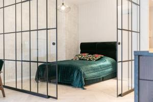 a bed in a room with a glass wall at VacationClub – Ogrody Pieniawskie Apartament 21 in Polanica-Zdrój