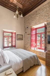 FOS Hydra residence في هيدرا: غرفة نوم بسرير كبير ونوافذ حمراء